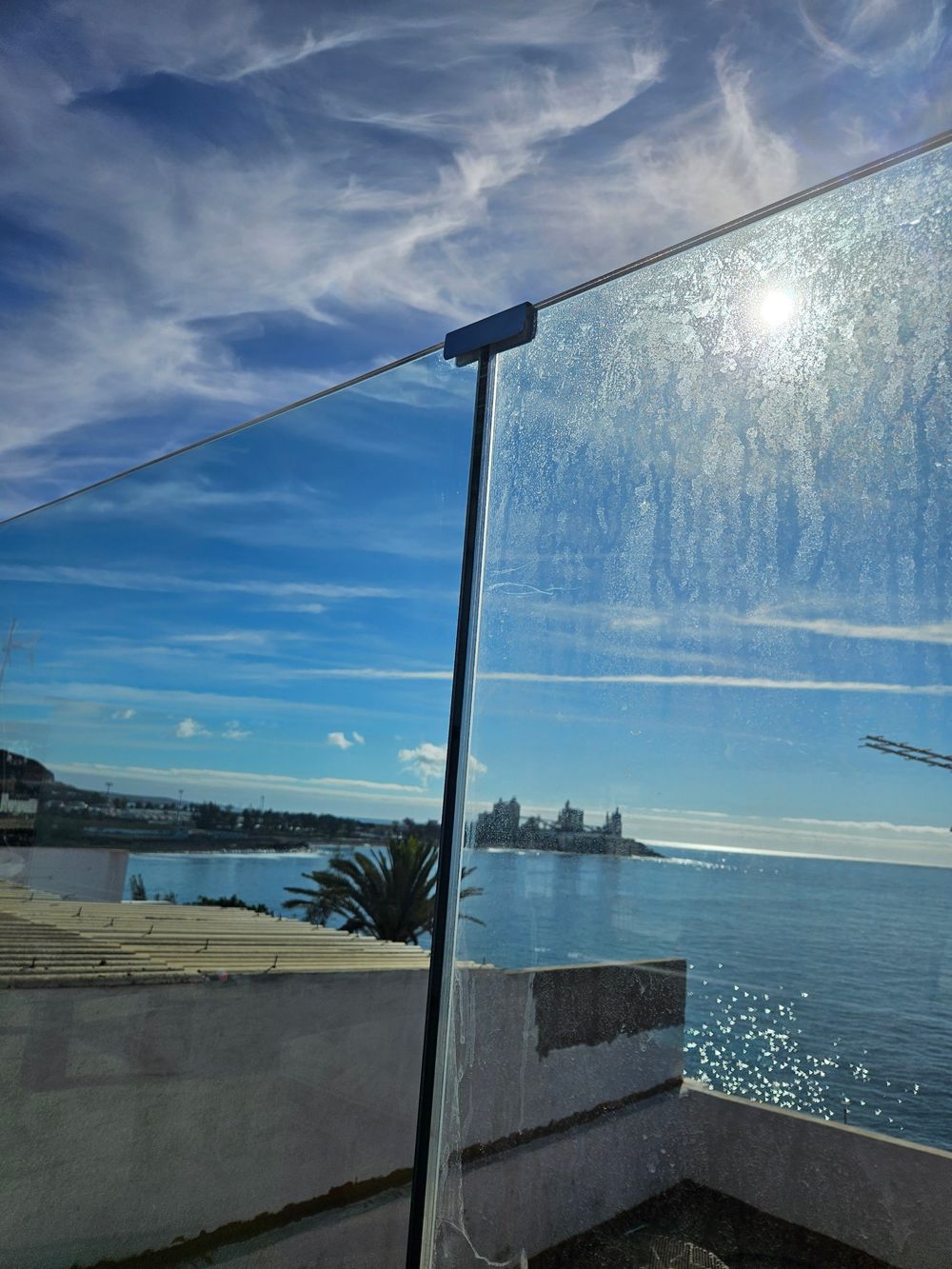 Cristal de barandilla mitad limpio y mitad sucio con vistas al mar