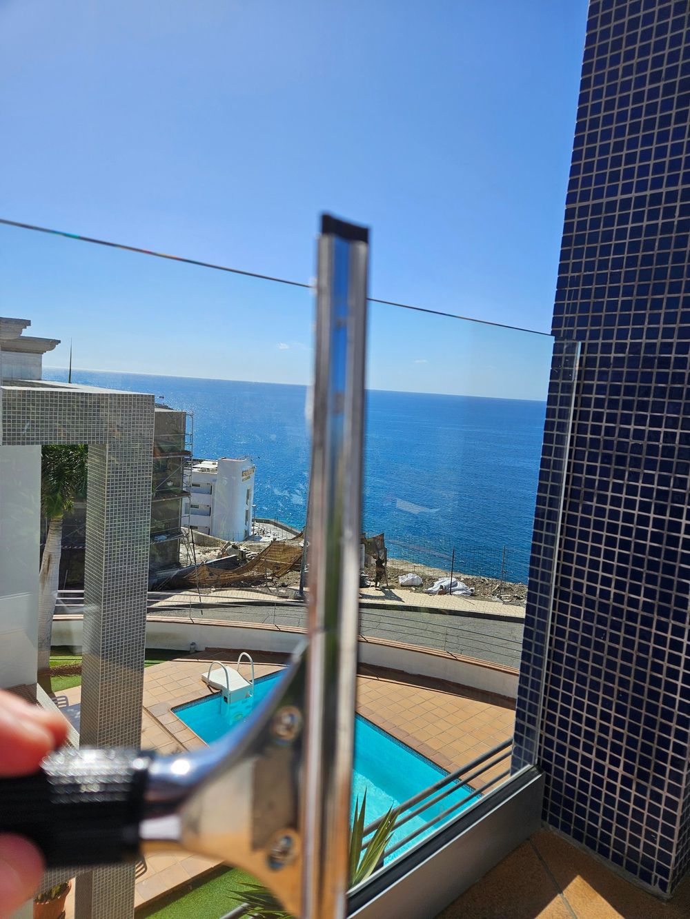 Limpiacristales profesional en una barandilla de cristal con vistas al mar