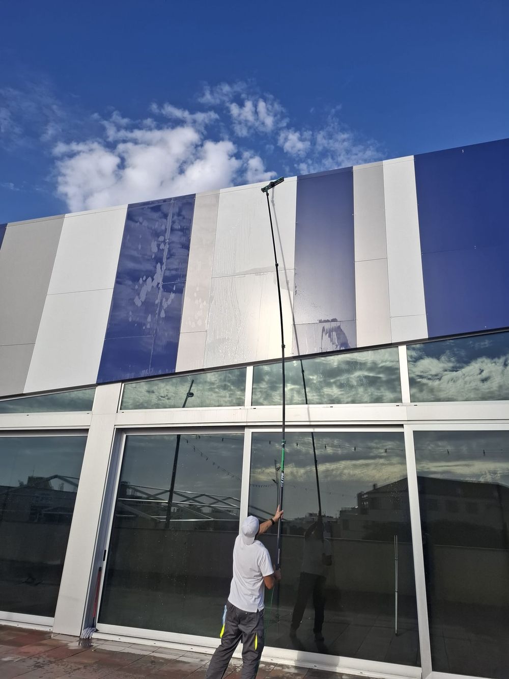 Operario limpiando paneles de fachada con pértiga
